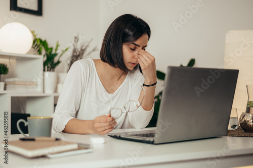 Woman feeling tired and stressed while using a laptop and working from home © Zamrznuti tonovi