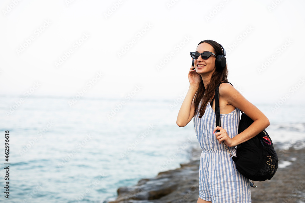 Hot woman relaxing on the sandy beach. Beautiful woman with headphones listening the music