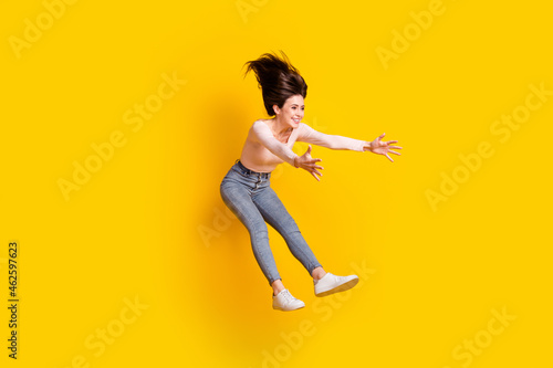 Full size photo of young lovely crazy smiling excited girl jumping catch surprise present isolated on yellow color background