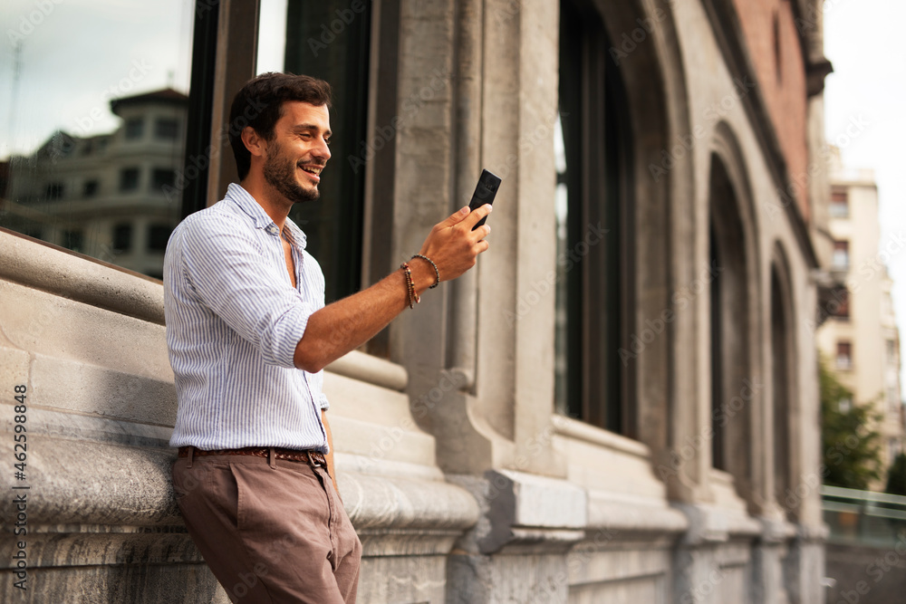 Young stylish man using the phone outdoors. Fashion happy man  enjoy outdoors