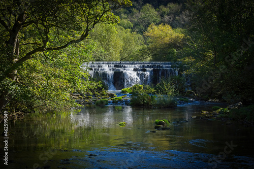 The River Wye tumbles over an almost hidden weir in Monsal Dale. photo