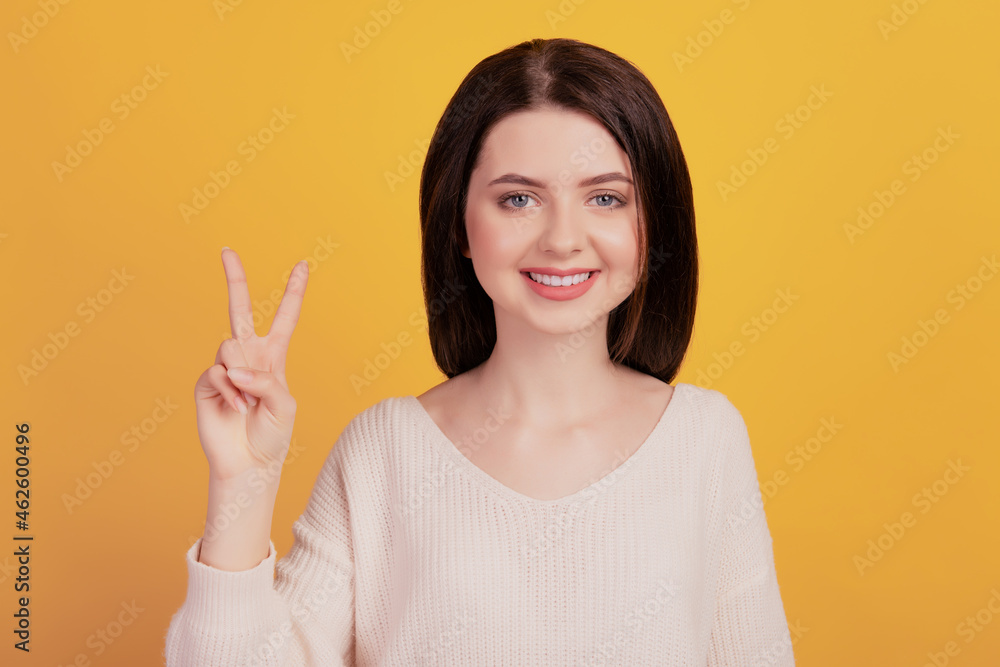Photo of young cheerful girl good mood show fingers cool peace v-symbol isolated on yellow color background Photo of young cheerful girl good mood show fingers cool peace v-symbol isolated on yellow color background