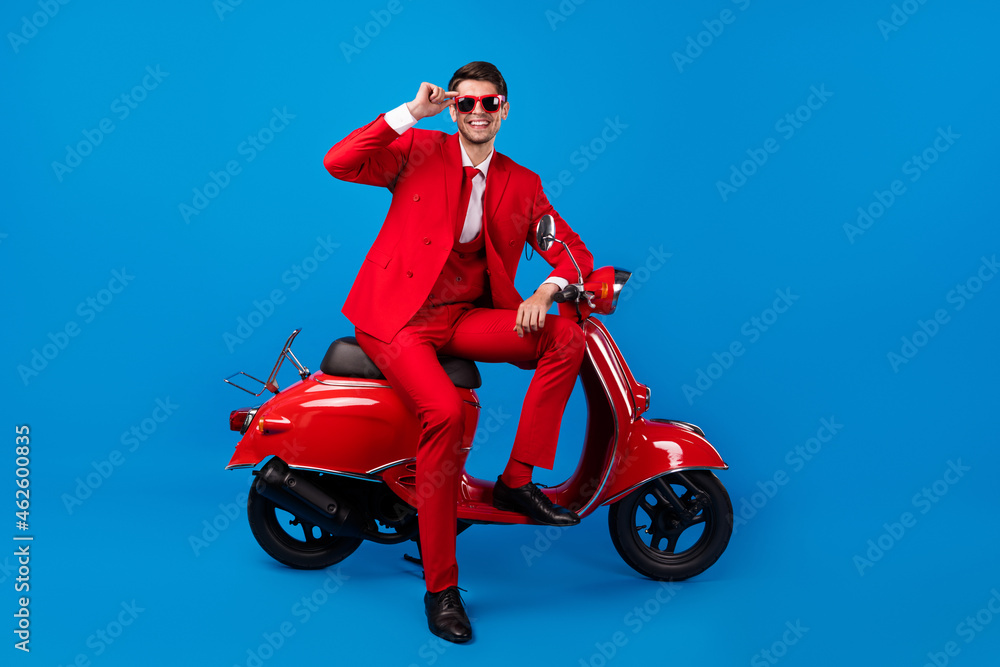 Full length photo of young handsome guy happy positive smile sit bike cool sunglass isolated over blue color background Full length photo of young handsome guy happy positive smile sit bike cool sunglass isolated over blue color background