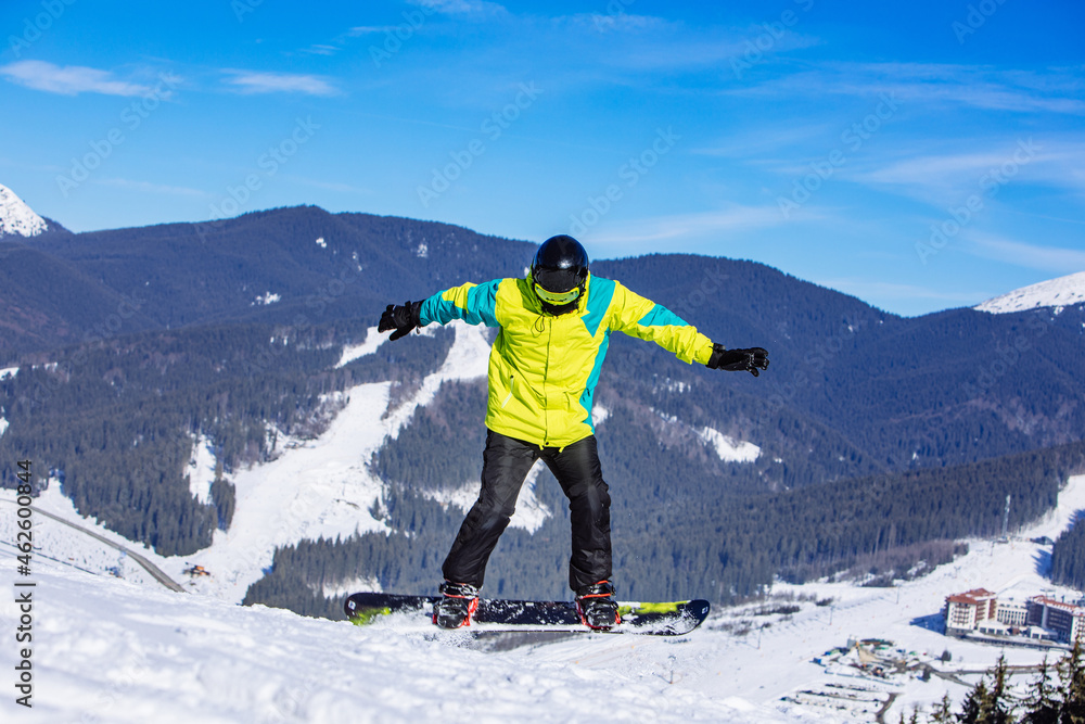 man in green coat jumping with snowboard