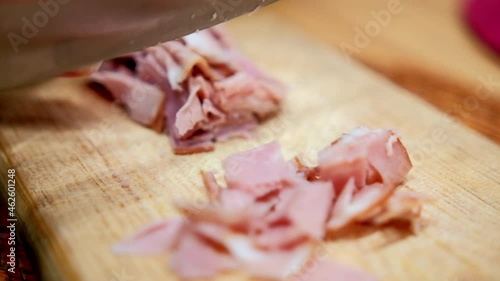 Hands chopping fresh turkey ham slices on a cutting board