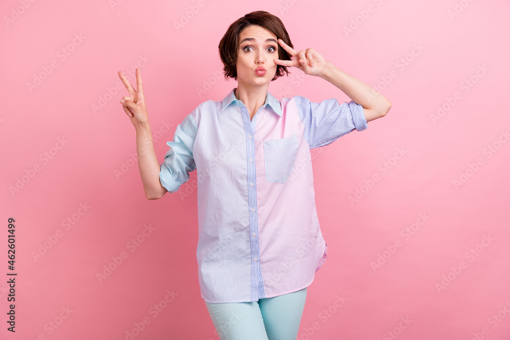 Photo portrait woman happy showing v-sign gesture sending air kiss isolated pastel pink color background Photo portrait woman happy showing v-sign gesture sending air kiss isolated pastel pink color background