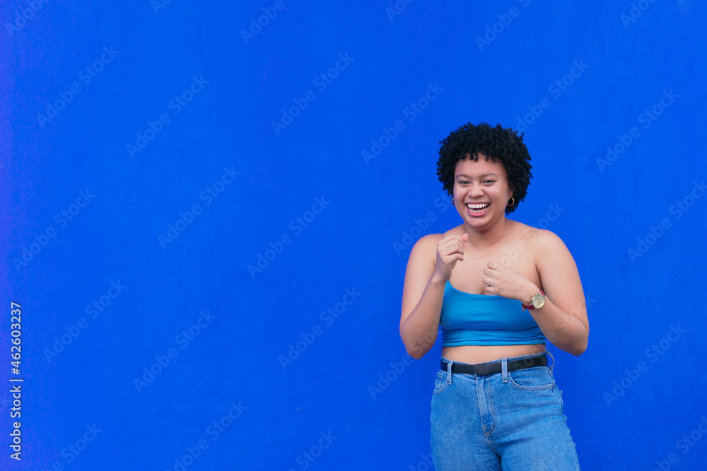 Young Hispanic girl, smiling with afro hairstyle and wearing a blue blouse. Young Hispanic girl, smiling with afro hairstyle and wearing a blue blouse.