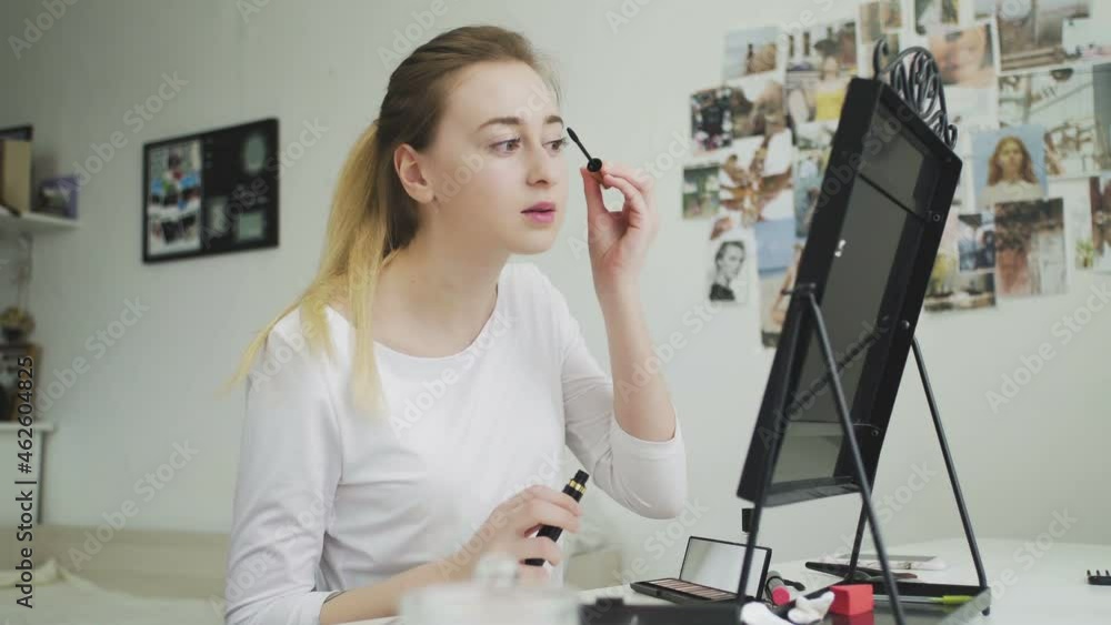 Make-up on the face. A young woman paints her long eyelashes with black mascara. Make-up on the face. A young woman paints her long eyelashes with black mascara.