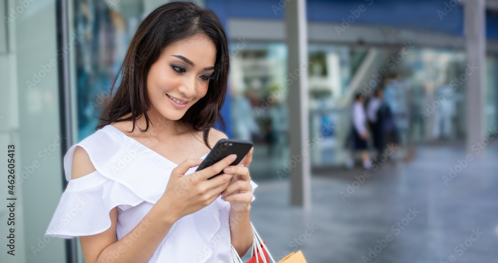 Portrait Asian beautiful happy young woman smiling cheerful and she using smartphone paymetn for shopping online with shopping bags Portrait Asian beautiful happy young woman smiling cheerful and she using smartphone paymetn for shopping online with shopping bags