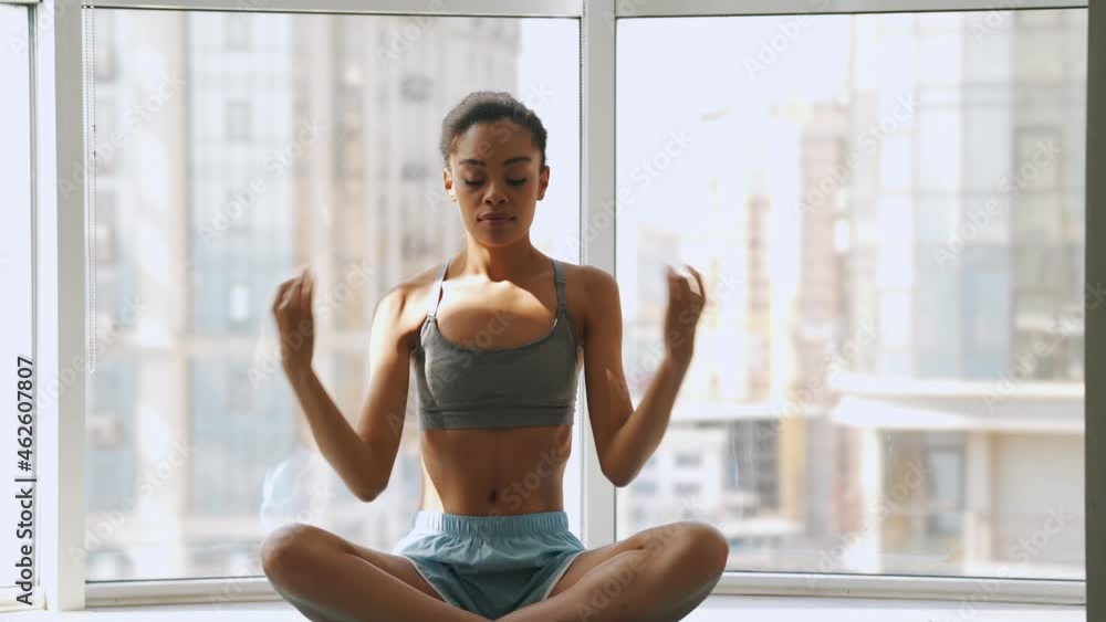 Concentrated african woman doing yoga exercises while sitting on the mat Concentrated african woman doing yoga exercises while sitting on the mat