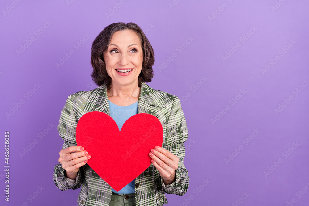 Photo of dreamy amazed charming old woman hold hands paper figure look empty space isolated on violet color background Photo of dreamy amazed charming old woman hold hands paper figure look empty space isolated on violet color background