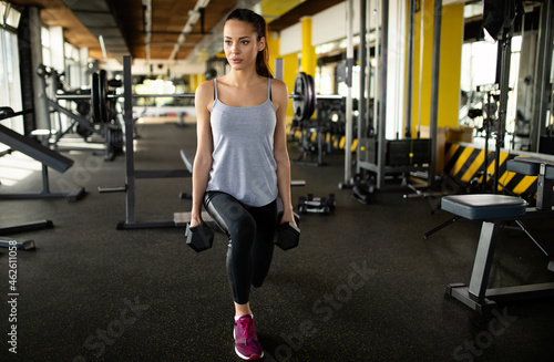 Beautiful fit woman exercising building muscles in gym. Sport health people concept