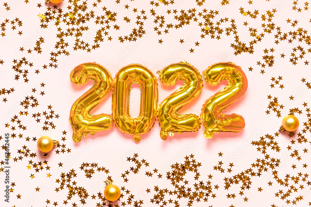 Gold foil balloons 2022 and glitter stars baubles on pink background. Happy New 2022 Year concept Gold foil balloons 2022 and glitter stars baubles on pink background. Happy New 2022 Year concept
