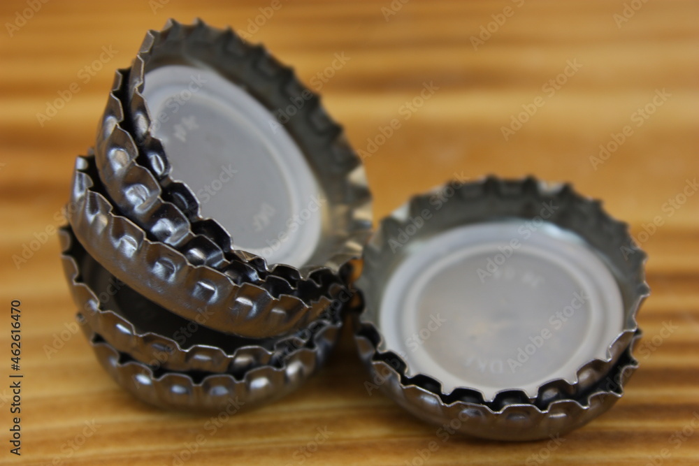Bottle caps stacked on a flamed wooden board Bottle caps stacked on a flamed wooden board