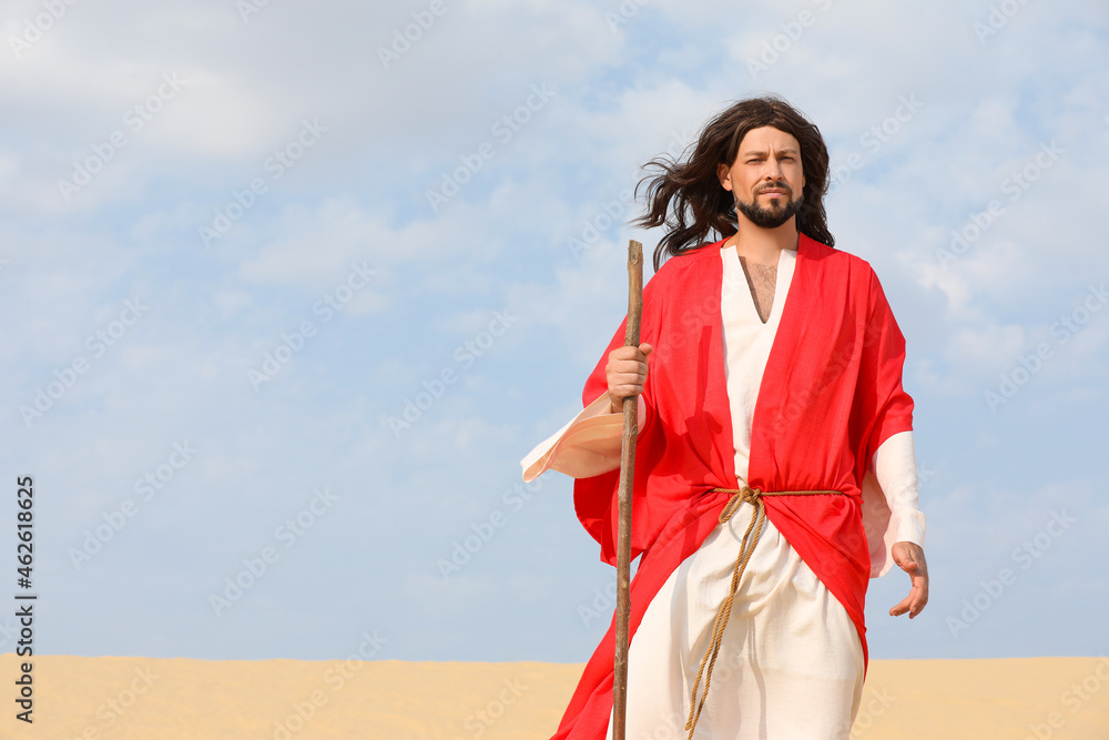 Fototapeta premium Jesus Christ walking with stick in desert. Space for text