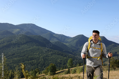 Tourist with backpack and trekking poles hiking through mountains, space for text © New Africa