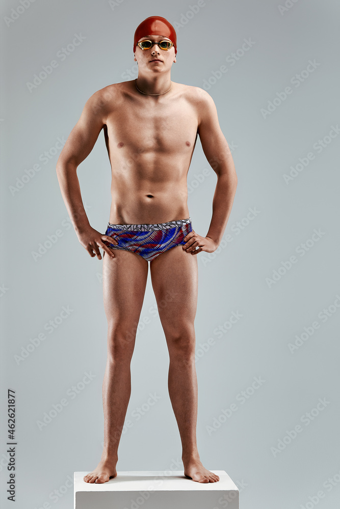 Young athletic man ready to jump into swimming pool against gray background. The concept of swimming and water games.