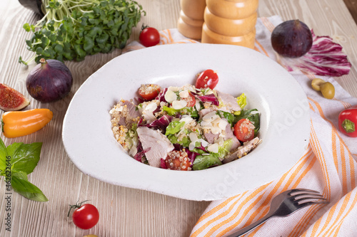 Salad with pork, quinoa, cherry tomatoes, and almond slices.