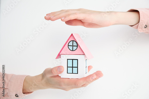 Hands use their hands to protect the red roofs, the concept of protecting houses using the gestures and symbols of real