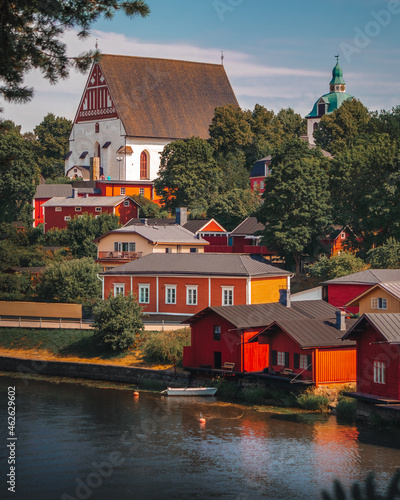 Old town of Porvoo in Finland. Townscape. Colorful wooden houses on a slope near river. Stone church standing on a hill. Traditional Finnish architecture. Scandinavian red buildings on the riverside.  photo