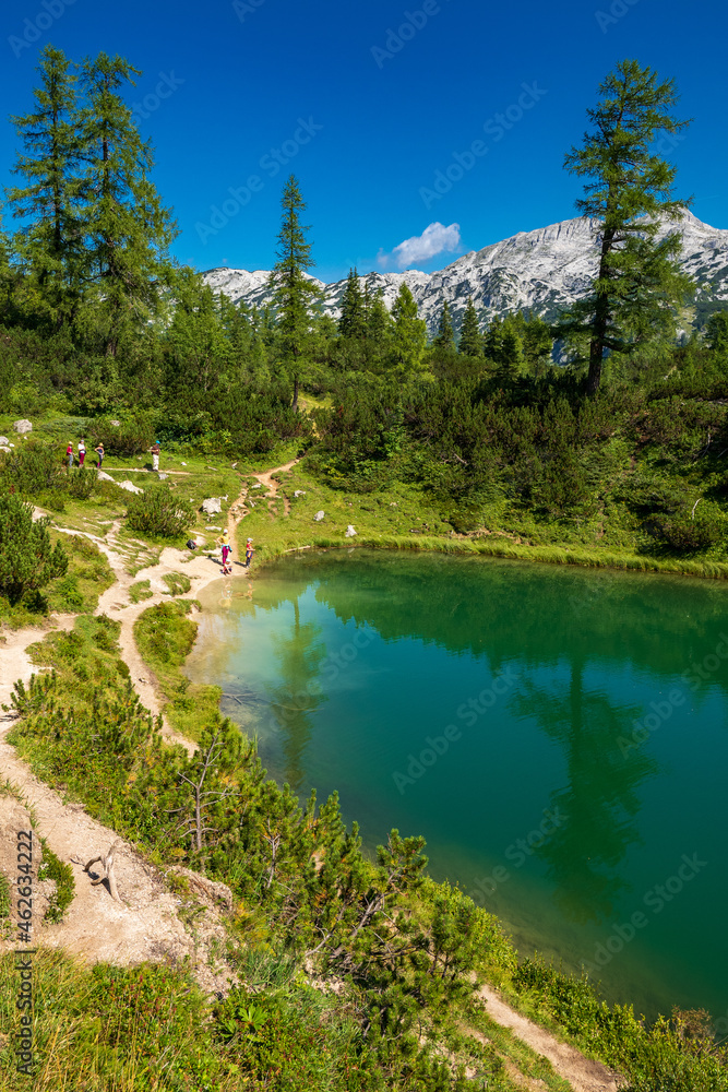 Hikers exploring the shore of the mountain lake Märchensee, literally fairy tale lake, on the Tauplitzalm plateau, Tauplitz, Ausseer Land, Austria