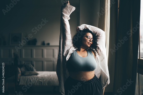 Fotografiet Curly haired plus size woman wearing comfortable clothes dances in stylish room