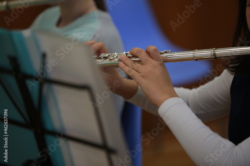 Child playing flute.Fingers of a girl of a young musician on the valve of a silver musical instrument close-up selective focus