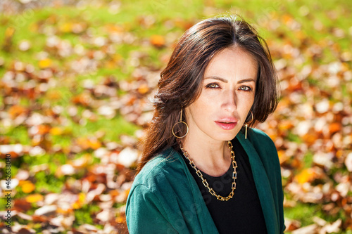 Portrait of a young beautiful brunette woman in autumn park