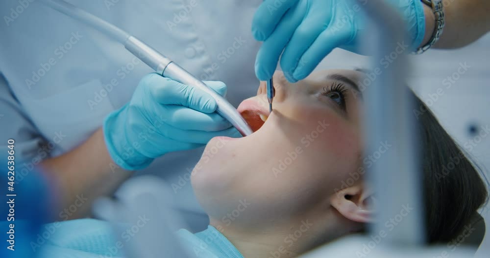 A dentist takes a machine for drilling teeth and starts treatment A dentist takes a machine for drilling teeth and starts treatment