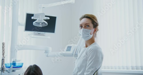 A woman dentist looks directly into camera while sitting in dental office photo