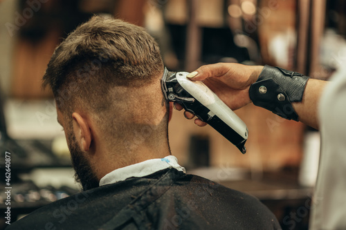 Young bearded man getting haircut by hairdresser