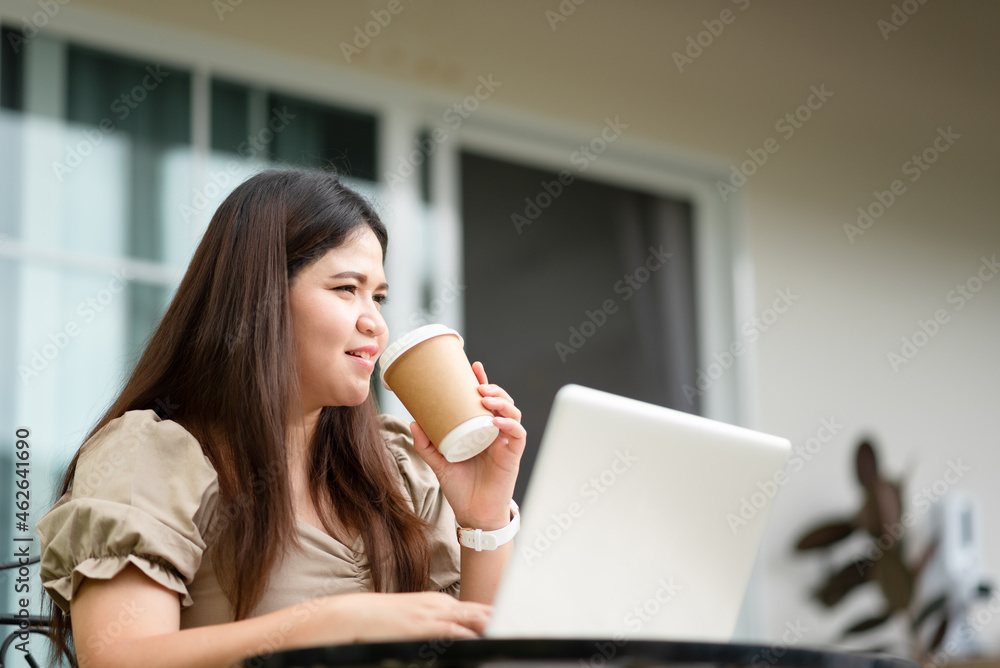 Asian woman is using her laptop to check email and work via the internet with a coffee next to her ,Working from home concept. Asian woman is using her laptop to check email and work via the internet with a coffee next to her ,Working from home concept.