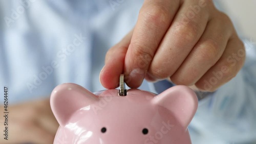 Close up of woman putting money coins saving in pink piggy bank for concept investment mutual fund finance and business photo
