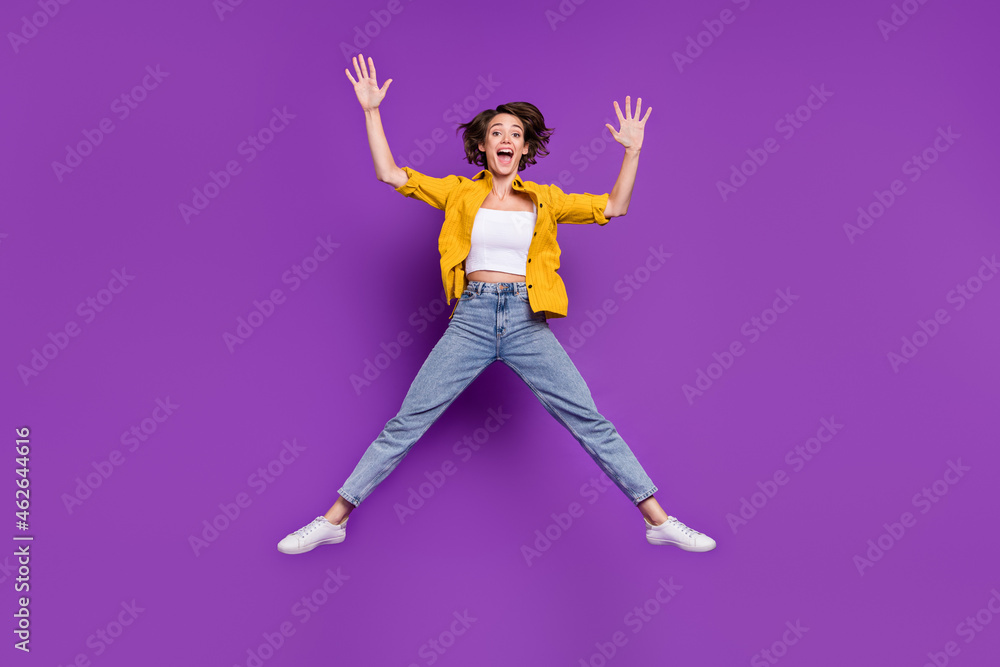 Photo of charming funny young lady wear yellow shirt jumping high smiling isolated violet color background Photo of charming funny young lady wear yellow shirt jumping high smiling isolated violet color background