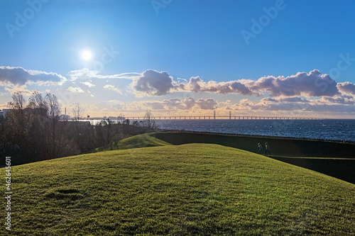 Malmo, Sweden. View on Oresund Bridge from the coast of Oresund strait in the Vastra hamnen neighbourhood of the city. Setting sun shines directly into lens. photo