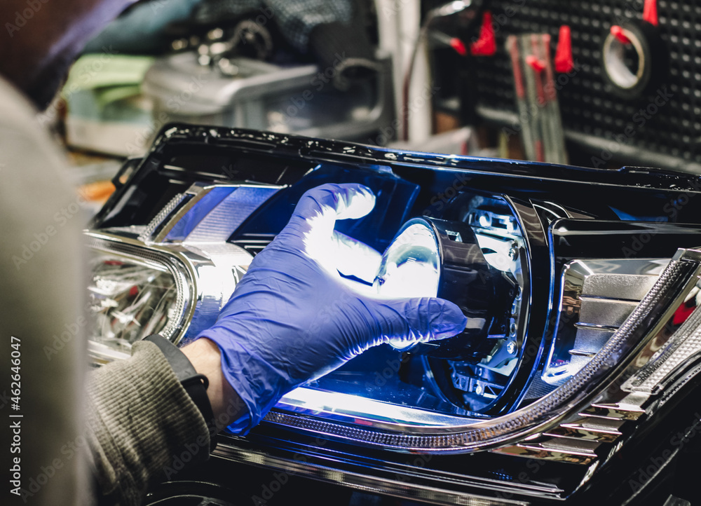 Car headlight in repair closeup.An auto mechanic wearing gloves checks