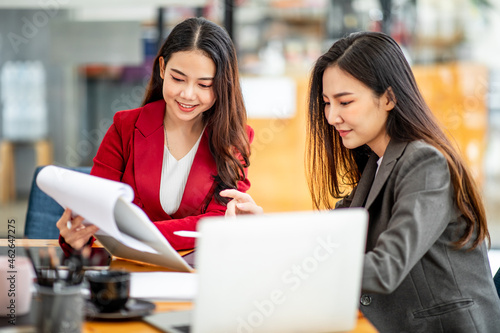 Two business Asian young women working together with laptop computer in the modern office.