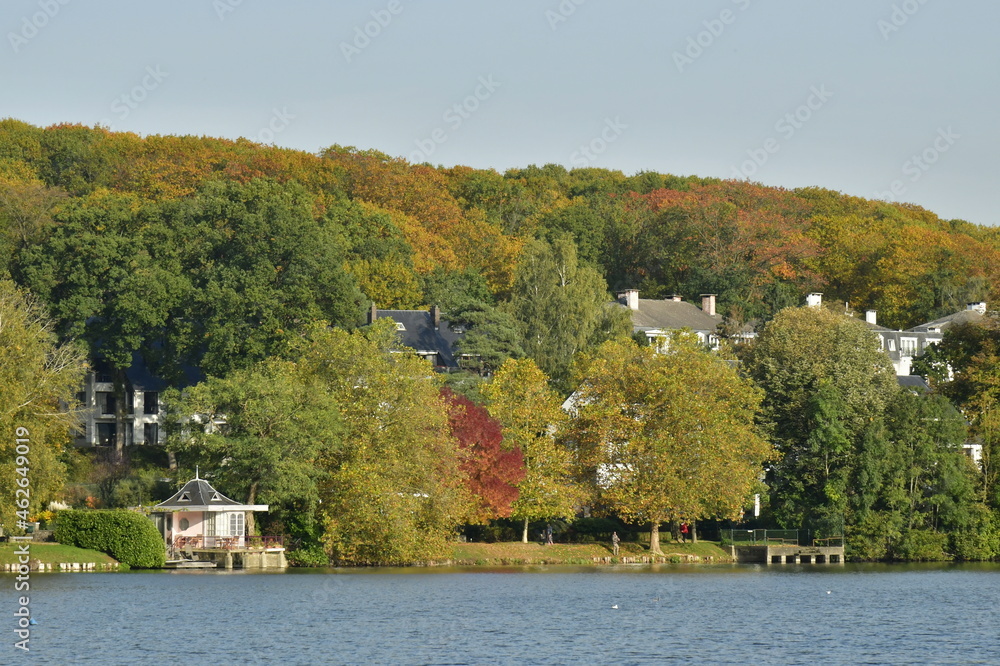Obraz premium Le lac de Genval dans un cadre bucolique avec ses villas et immeubles à appartements dissimulés dans la nature luxuriante qui l'entoure en automne