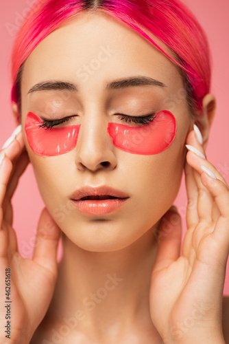 young woman with closed eyes and collagen eye patches isolated on pink