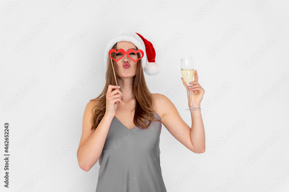 Funny girl wears Santa's hat wears pretend heart glasses holds glass of champagne. New Year party Funny girl wears Santa's hat wears pretend heart glasses holds glass of champagne. New Year party