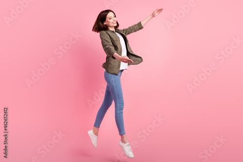 Full length photo of sporty brunette hairdo lady dance wear khaki shirt jeans sneakers isolated on pink color background