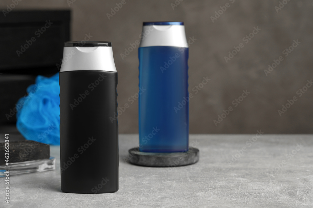 Bottles of shower gel on grey table. Space for text Bottles of shower gel on grey table. Space for text