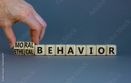 Moral or ethical behavior symbol. Businessman turns cubes, changes words ethical behavior to moral behavior. Beautiful grey background, copy space. Psychology, moral or ethical behavior concept.