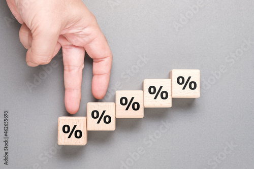 Closeup hand gesture as fingers walking step up on the wood cubes with percentage symbol, commission increase, insurance, and savings photo