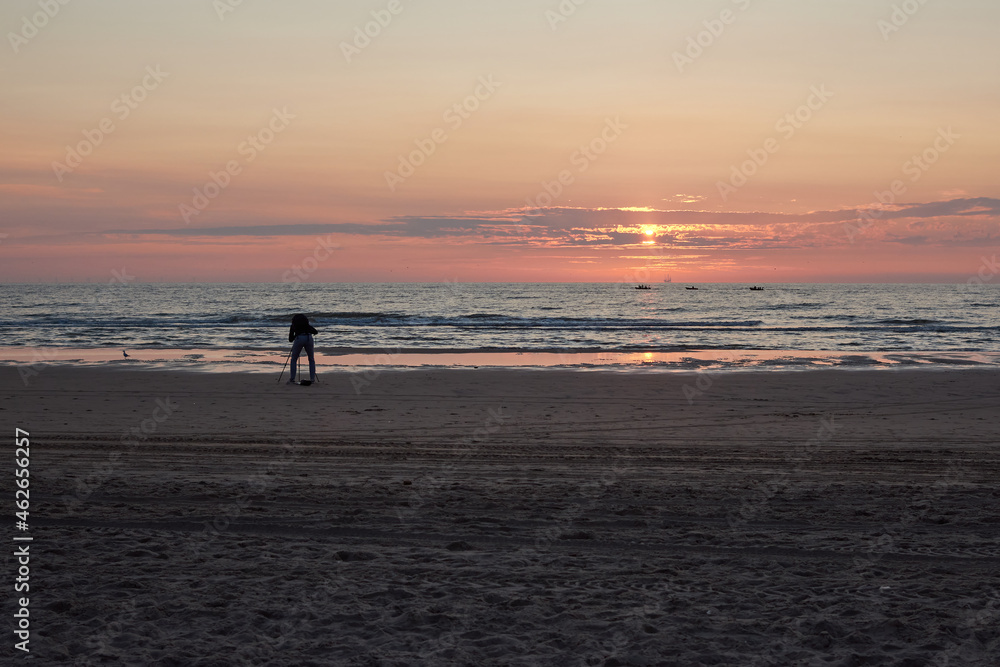 A photographer at the beach enjoying the scenic sunset