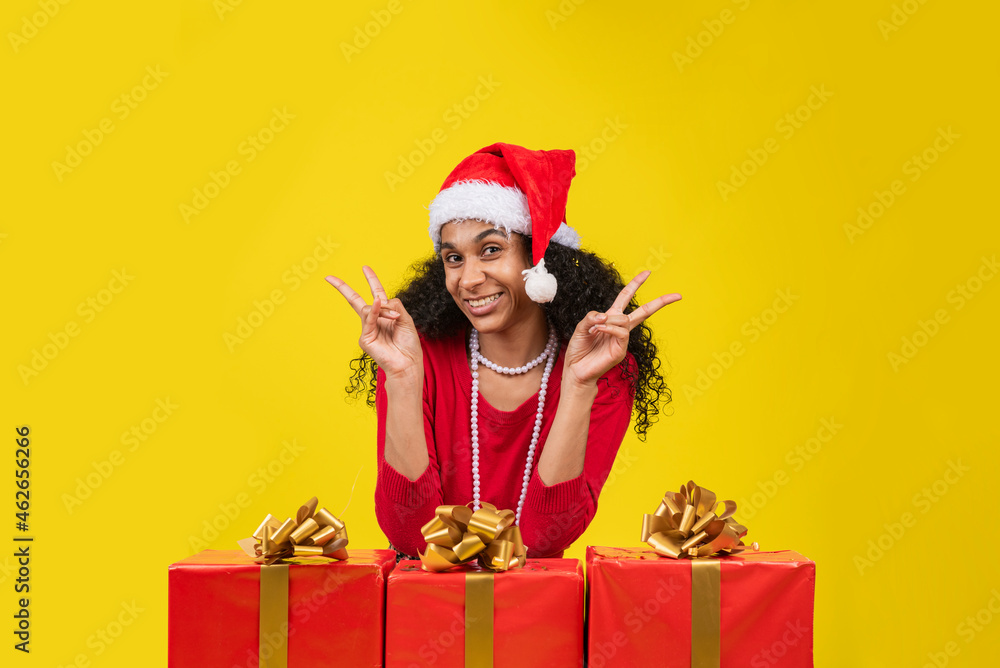 mujer afroamericana con gorro navideño y regalos en fondo amarillo Stock  Photo | Adobe Stock