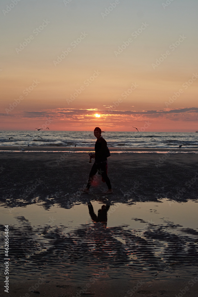 A vertical shot of a cheerful Caucasian lady from Spain enjoying sunset at the beach