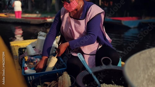 Female food vendor preparing traditional street corn in yellow boat