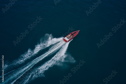 Diagonal boat movement on blue water top view. Red speed boat fast movement on the water top view. Travel - image. Top view of a red fast boat.