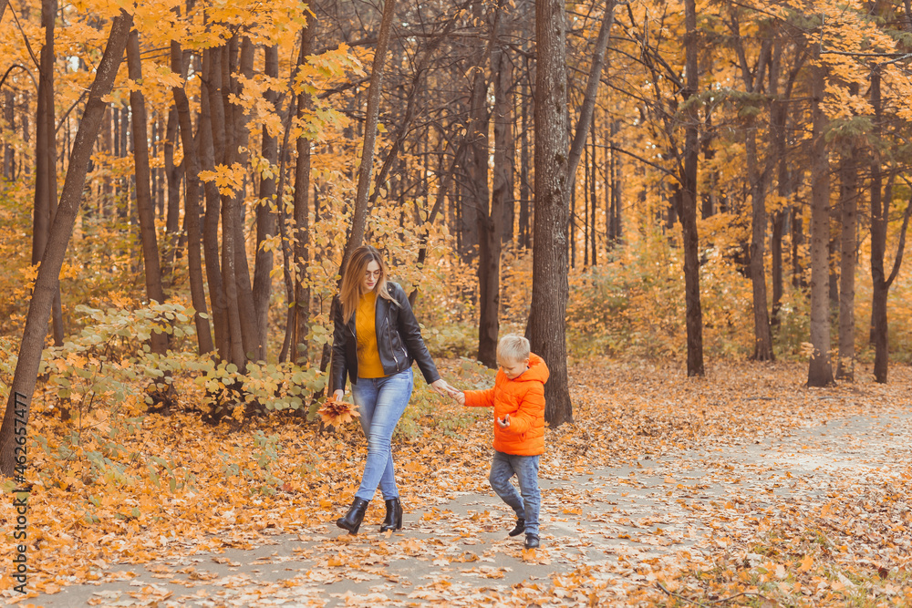 Mother and son walking in the fall park and enjoying the beautiful autumn nature. Season, single parent and children concept. Mother and son walking in the fall park and enjoying the beautiful autumn nature. Season, single parent and children concept.
